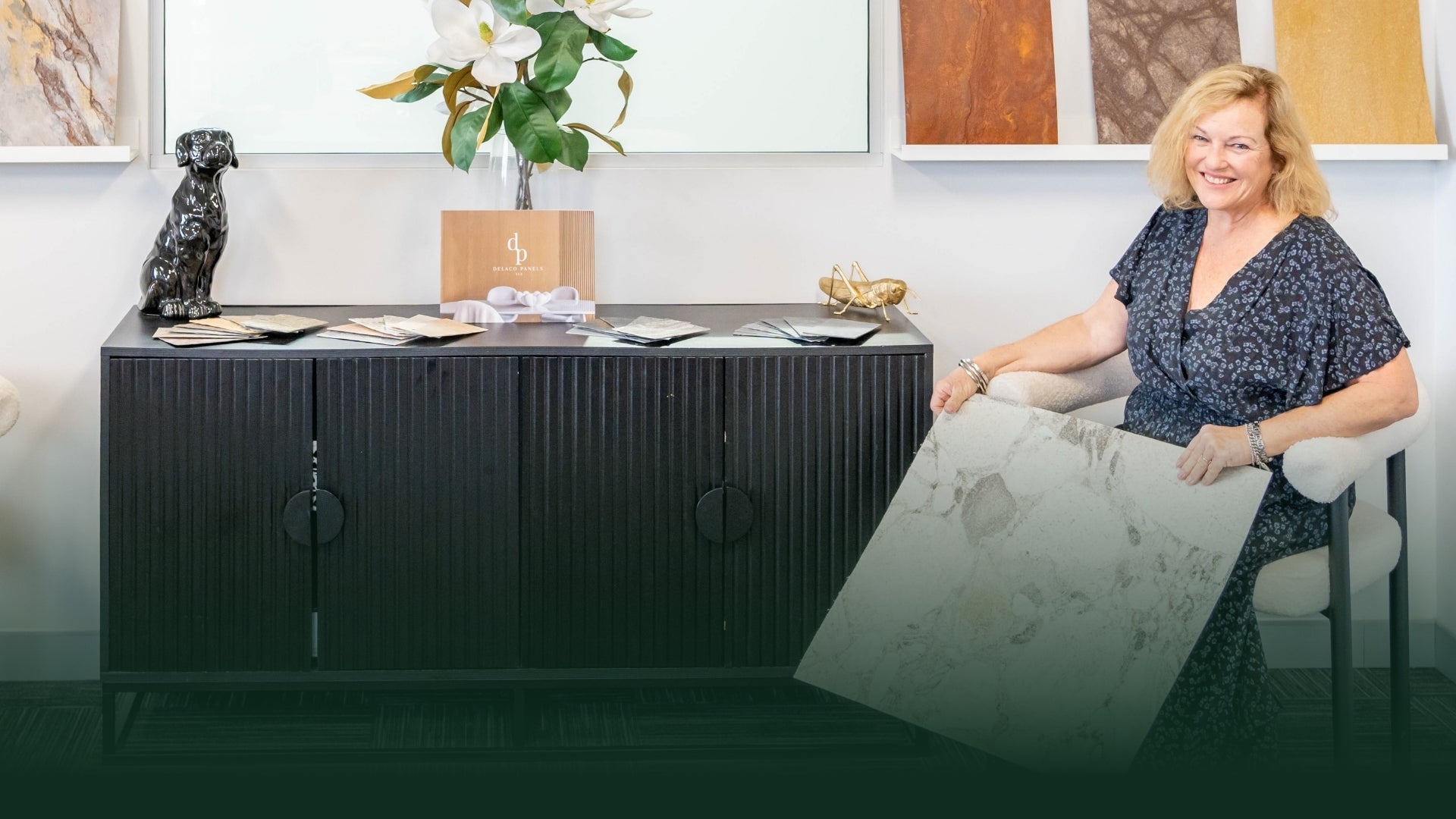 Woman sitting at a modern black desk with decorative items and artwork in the background. Showroom